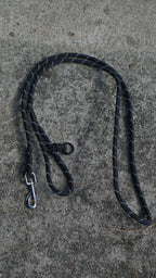 Black dog leash with metal clip on a concrete surface